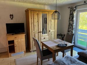 a living room with a dining table and a television at Haus Chiemseeblick in Grabenstätt