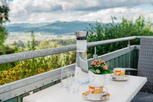 a table with two cups and a vase on a balcony at Ferienwohnungen Lusenblick in Freyung