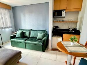 a living room with a green couch and a table at Flat confortável com recepção 24h e vaga de garagem in São Paulo