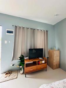 a room with a television on a dresser in front of a window at ALCA Homestay in Palo