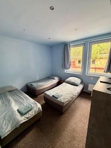 two beds in a room with two windows at Pokoje przy Żaglach in Rybnik