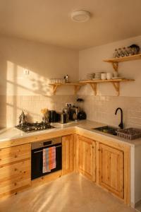 a kitchen with wooden cabinets and a stove at Yara Lodge in Tamraght Ou Fella