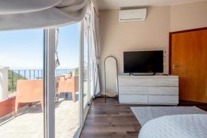 a bedroom with a bed and a tv and a balcony at Casa do Castanheiro in Campanário