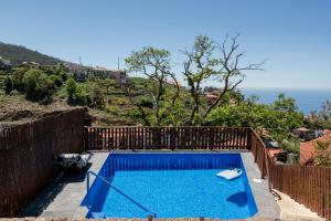 a swimming pool on a hill with the ocean in the background at Casa do Castanheiro in Campanário