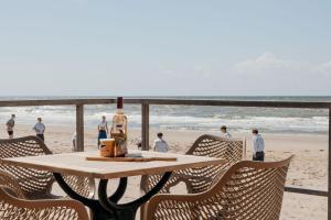 a table with a bottle of wine and chairs on the beach at Puur Petten in Petten
