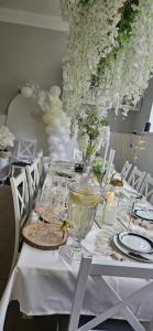 a white table with white chairs and flowers on it at Domek Pod Grzybkiem in Dźwierszno Małe