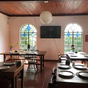 a dining room with tables and chairs and two windows at Jardim da Marambaia in Barra de Guaratiba