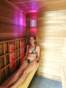 a woman is sitting in a sauna at Le Castelet Sancy - Jardin & Spa in Le Mont-Dore