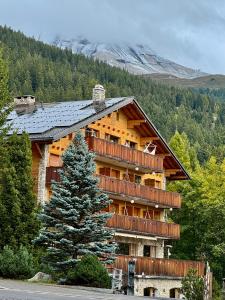 a large log cabin building with a tree in front of it at Colorado Riders Chalet in Crans-Montana