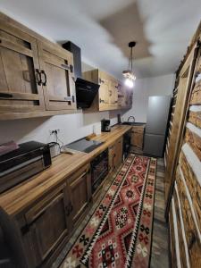 a kitchen with wooden cabinets and a rug on the floor at Cerdacul cu Amintiri in Câmpulung Moldovenesc