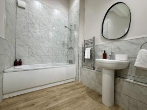 a bathroom with a tub and a sink and a mirror at Hazel, Spacious 3-Bed Home in Dowlais