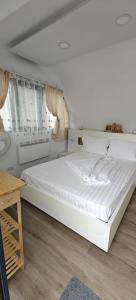 a large white bed in a room with a table at La Coca Lake House in Bicaz