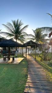 a path with umbrellas and benches and palm trees at POUSADA PONTA DA ASA in Coruripe