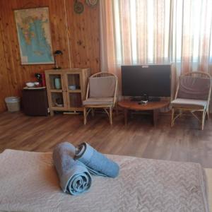 a bedroom with a bed and a television and chairs at Rising Sun Guesthouse in Mesokhória