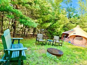 a group of chairs sitting in the grass next to a tent at Camp Squid Off The Grid in Benzonia