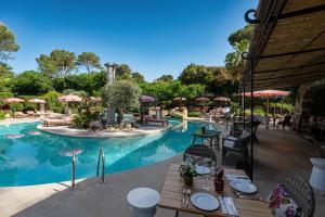 a resort with a pool with a table and chairs at Hotel Les Messugues in Saint Paul de Vence