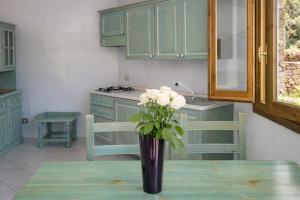 a vase with white roses on a table in a kitchen at Hotiday Apartments Orosei in Cala Liberotto