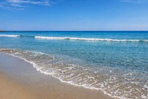 a sandy beach with waves in the ocean at Hotiday Apartments Orosei in Cala Liberotto