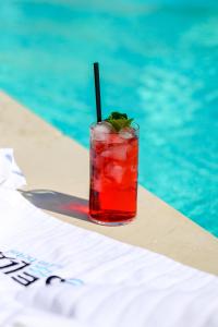 a drink sitting on a table next to a swimming pool at Mosella Suite Hotel - A Lagoon Retreat in Sottomarina