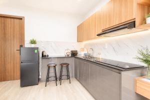 a kitchen with a refrigerator and two bar stools at Fame Apartment in Dong Hoi