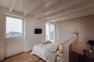 a white room with a bed and two windows at Casa dei Bruschi in Casarza Ligure