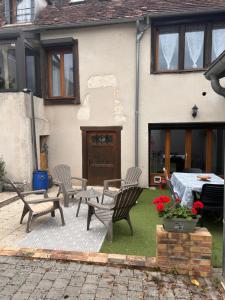 a patio with three chairs and a table and a table and a grill at Gîte de l horloge in Déols