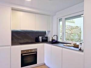 a kitchen with white cabinets and a microwave and a window at YourHouse O Canelar in Allariz