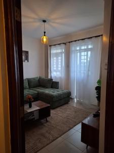 a living room with a green couch and a table at Serene 63 Luxe in Murangʼa