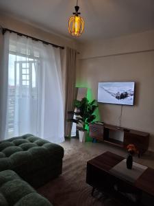a living room with a couch and a flat screen tv at Serene 63 Luxe in Murangʼa