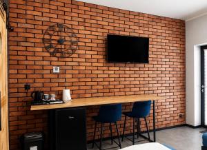 a television on a brick wall with a bar and stools at Noclegi Na Końcu Świata Bielpon in Przemyśl