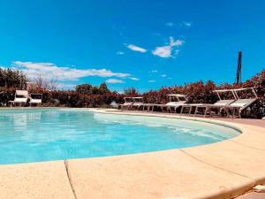 a swimming pool with chairs and blue water at B&B La Vigna in Carovigno