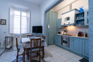 a kitchen with blue cabinets and a table with chairs at Green Square Apartment 14 Min from Santa Croce with Hydromassage Tub in Florence