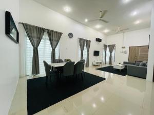 a dining room and living room with a table and chairs at D Azlin Homestay in Kuala Kangsar