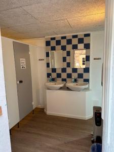 a bathroom with two sinks and a checkered wall at Stege Camping in Stege