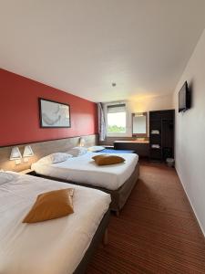 two beds in a hotel room with red walls at Hôtel Goodwood Caen Mémorial in Caen