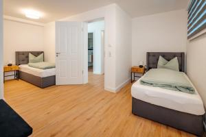 two beds in a room with wooden floors at Ferienwohnung Riethchaussee in Wingerode