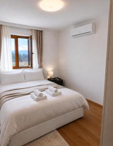 a bedroom with a white bed with towels on it at Luxury Apartment-Aurora 33 Free Parking City Center in Podgorica