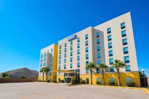 a hotel with palm trees in a parking lot at City Express by Marriott Hermosillo Expo in Hermosillo