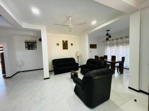 a living room with black furniture and a dining room at Amantha Holiday Resort in Anuradhapura