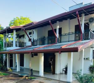 a white building with a second story with a balcony at Amantha Holiday Resort in Anuradhapura