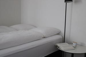 a white bed with a side table and a lamp at Aurora Studio Apartments in Nuuk