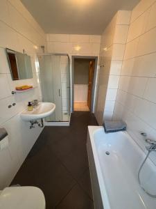 a bathroom with a tub and a sink and a toilet at Ferienwohnung Habichtweg in Elsdorf