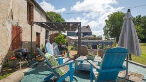 a group of chairs and an umbrella on a patio at Gîte Le Relais De Jehan in Saint-Malo des 3 Fontaines