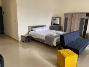 a bedroom with a bed and a chair and a mirror at Chalet 103 - Zresidence - Faitroun in Al ‘Aqabah