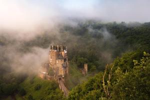 an old castle on a hill in the clouds at Gästehaus Frevel in Münstermaifeld