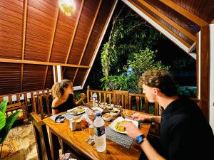 two people sitting at a wooden table eating food at Oak Haven Cabana Sigiriya in Sigiriya