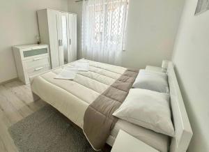 a white bedroom with a large bed and a window at Maver apartment in Mali Lošinj