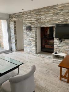 a living room with a stone fireplace with a tv at Sci Licorne d Or in Saint-Méloir-des-Ondes