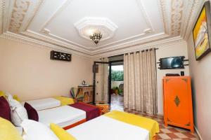 a room with three beds and a tv on the ceiling at Riad Saida Atlas in Marrakesh