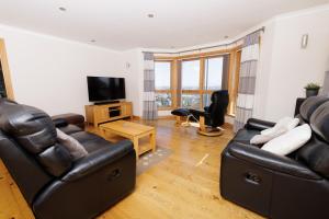 a living room with leather furniture and a flat screen tv at Quoys Self Catering, Shetland in Lerwick